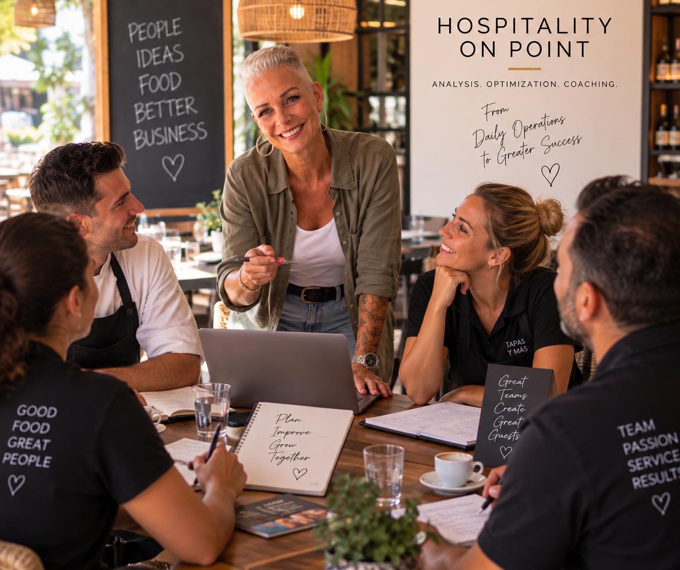 Renée Gorgoglione está de pie, riendo, con un bolígrafo en la mano junto a una mesa, rodeada de un cocinero con chaqueta blanca y tres empleados con polos negros, en el comedor de un restaurante.